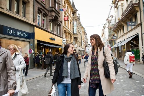 Zwei junge Frauen gehen gut gelaunt durch die Freie Strasse in Basel.